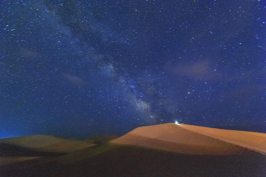 天地一体的鸣沙山沙漠世界,最高处的那盏灯与天空的银河遥相呼应