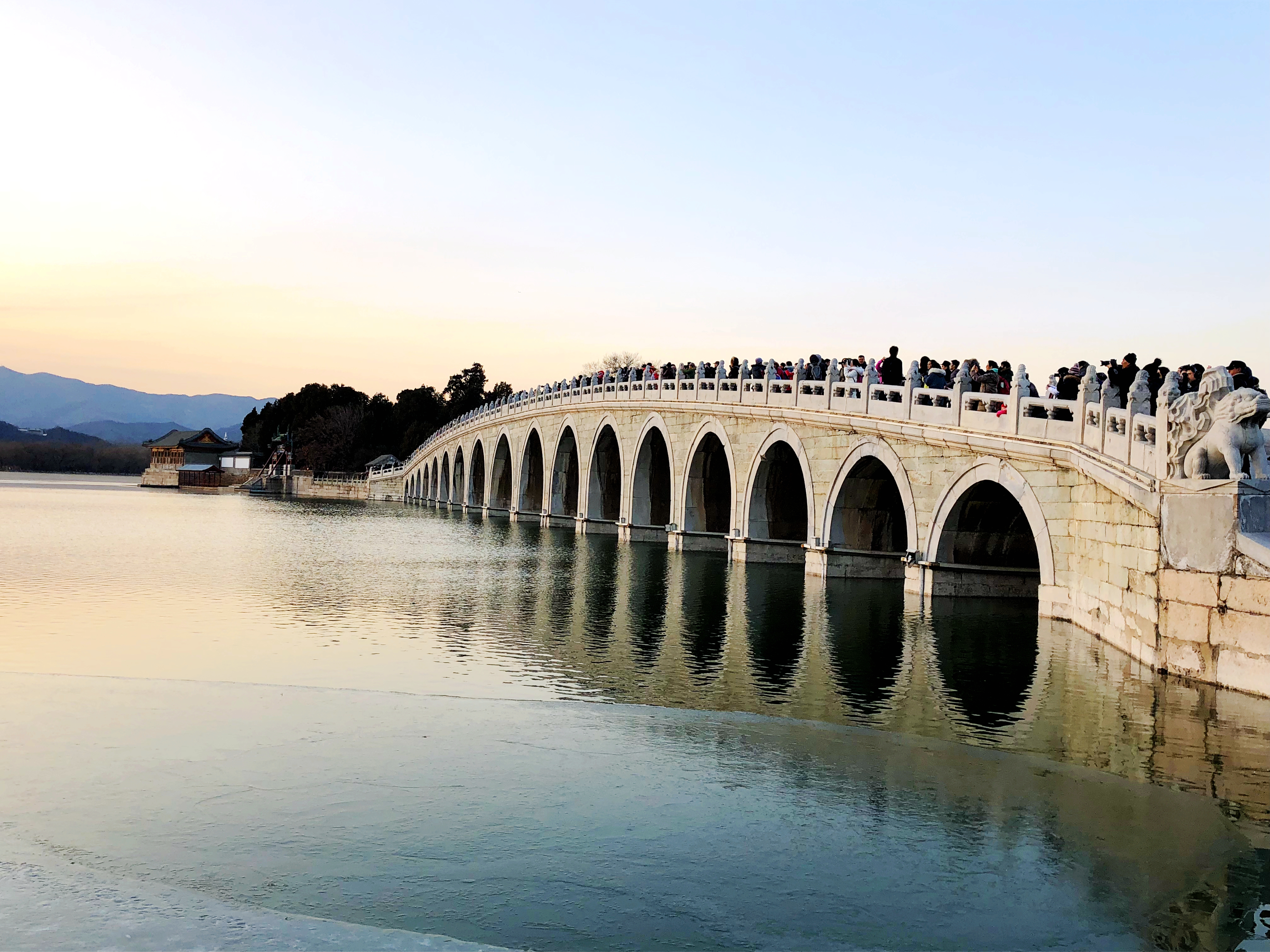 当日,北京颐和园十七孔桥出现"金光穿洞"美景,吸引许多游客和摄影