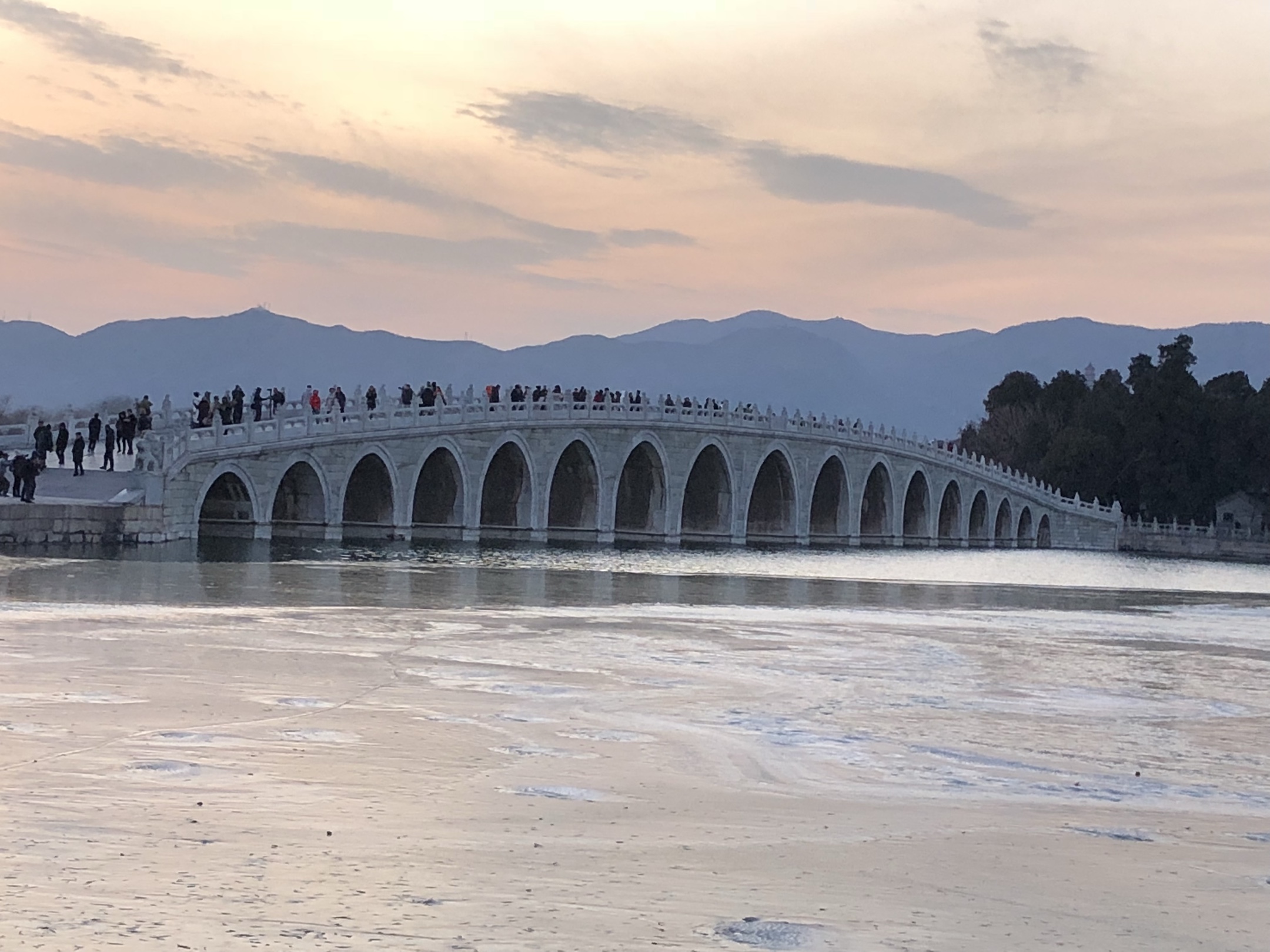 当日,北京颐和园十七孔桥出现"金光穿洞"美景,吸引许多游客和摄影