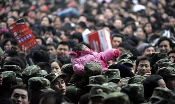 1日,武警战士从广州火车站密密麻麻的人群中把一个孩子手递手托举出来